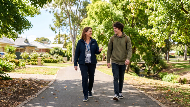 Support worker and person with disability walking in an inclusive community environment