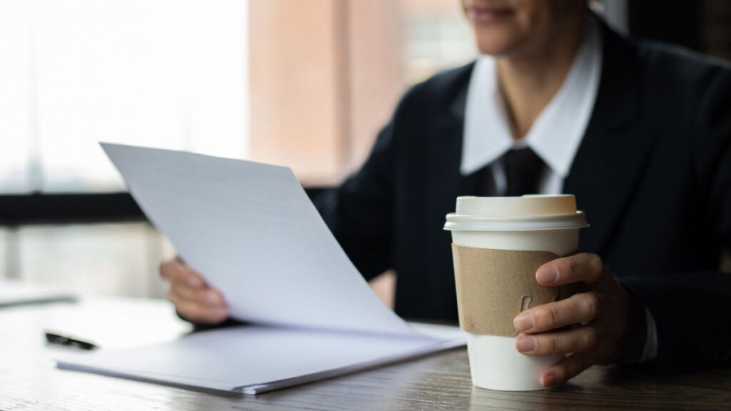 Person reviewing documents with coffee