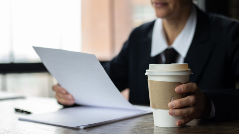 Person reviewing documents with coffee