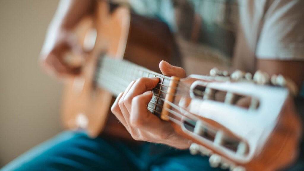 Person playing acoustic guitar in warm light